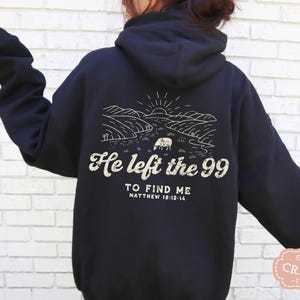 May include: Black hooded sweatshirt with a white graphic print of a landscape with a sheep and the text "He left the 99 to find me Matthew 18:12-14".