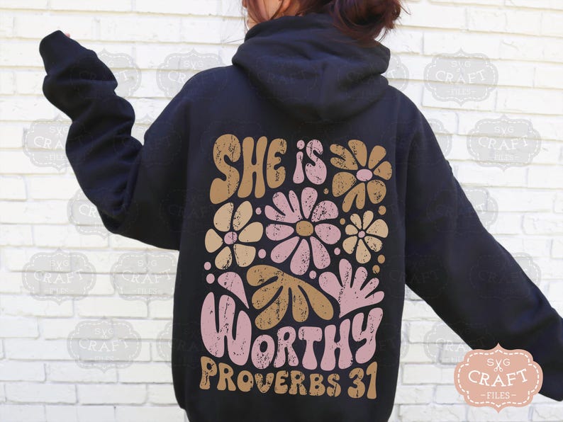 Puede incluir: Una sudadera con capucha negra con un dise&ntilde;o floral y el texto "She is Worthy Proverbs 31" en rosa y marr&oacute;n.