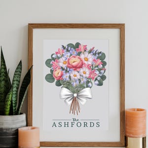 Puede incluir: Una impresi&oacute;n enmarcada con una ilustraci&oacute;n de acuarela de un ramo de flores rosas y blancas con hojas verdes y un lazo blanco. El texto "The Ashfords" est&aacute; impreso debajo del ramo.