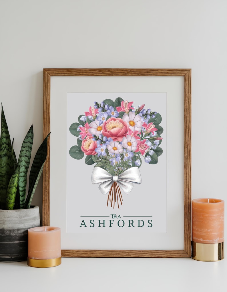 Puede incluir: Una impresi&oacute;n enmarcada con una ilustraci&oacute;n de acuarela de un ramo de flores rosas y blancas con hojas verdes y un lazo blanco. El texto "The Ashfords" est&aacute; impreso debajo del ramo.