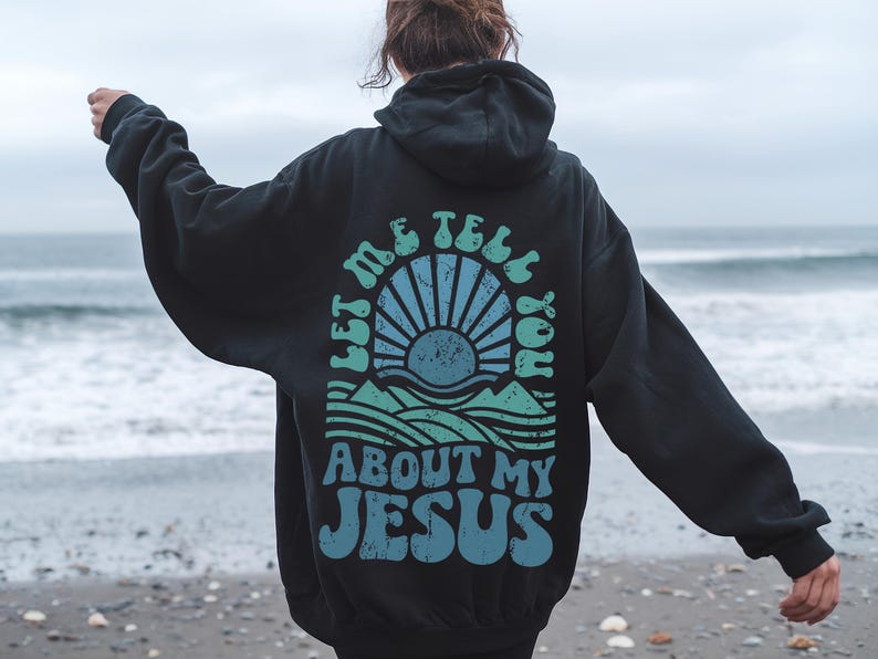 May include: Black hooded sweatshirt with a graphic print of a sunrise over a mountain range and the text "Let me tell you about my Jesus".