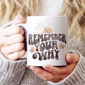 May include: White ceramic mug with a brown and white graphic that says "Remember Your Why" with a sun and hearts.