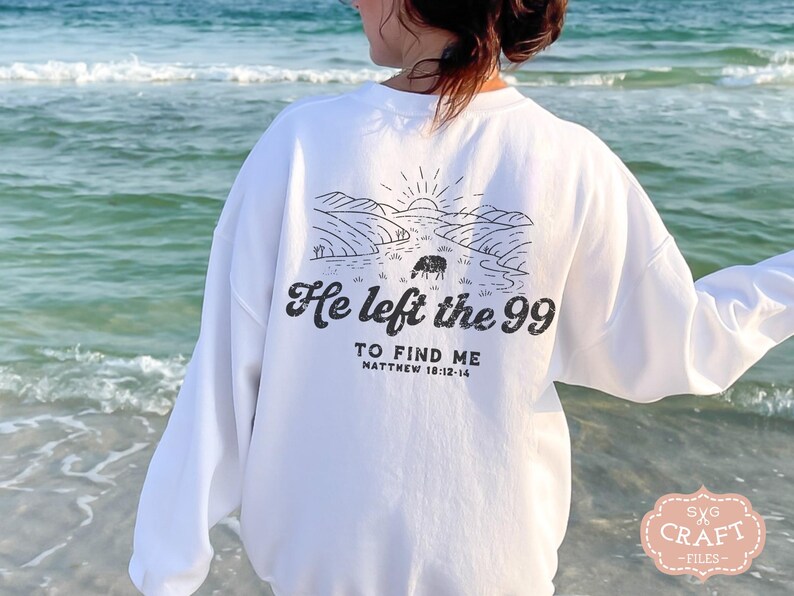 May include: White long-sleeve sweatshirt with a black graphic design of a landscape with a sheep and the text "He left the 99 to find me Matthew 18:12-14".