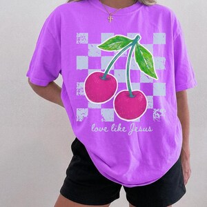 Trendy Christian shirt design with vibrant cherries and checkerboard accents.
