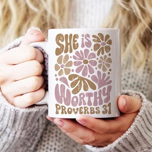 Puede incluir: Taza de cer&aacute;mica blanca con un dise&ntilde;o floral rosa y marr&oacute;n y el texto "She is worthy Proverbs 31".