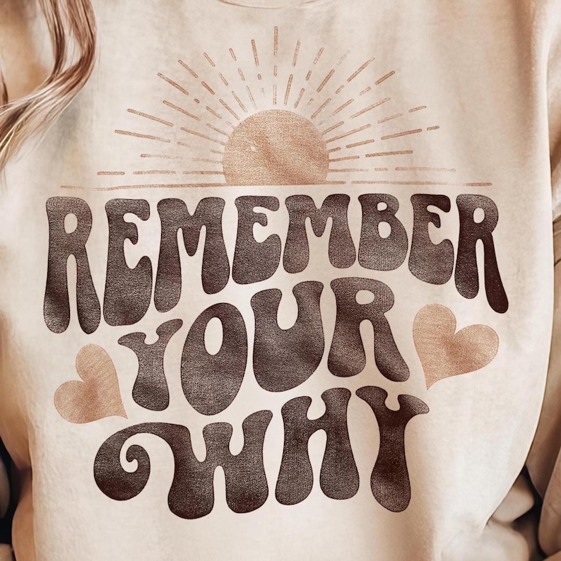May include: A beige sweatshirt with a brown graphic design that says "Remember Your Why" with a sun and two hearts.