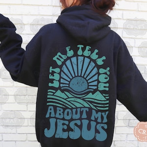 May include: Black hoodie with a graphic print of a sun setting over a mountain range. The text "Let me tell you about my Jesus" is printed in a retro font.