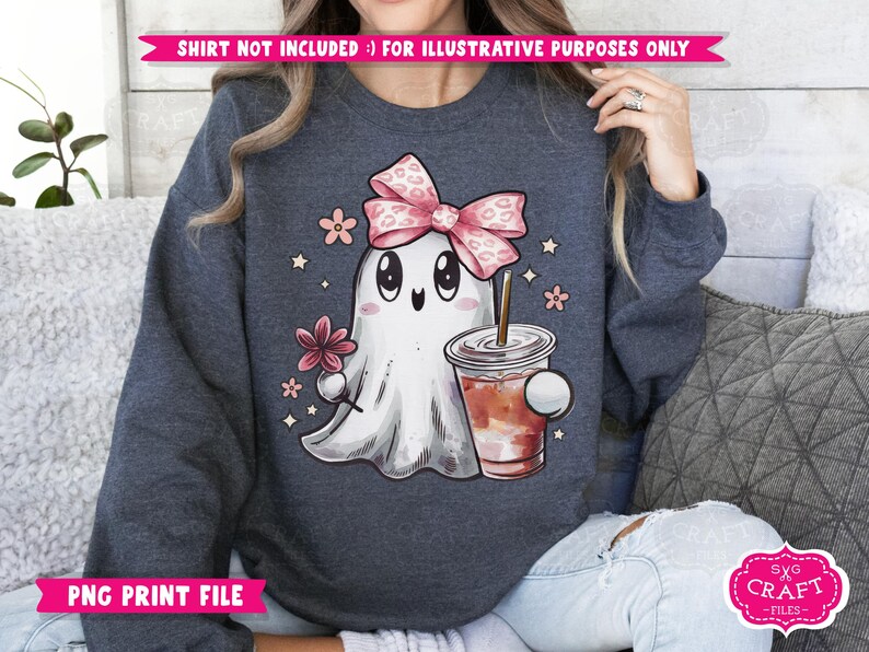 May include: A dark blue sweatshirt with a cute cartoon ghost wearing a pink bow and holding a cup of coffee. The ghost has a friendly face and is surrounded by small pink flowers.