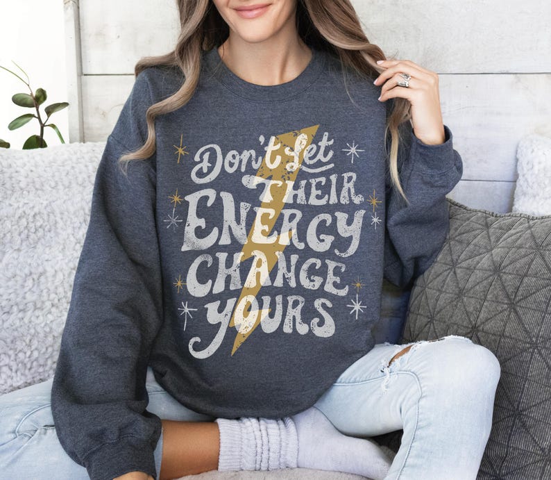 May include: A dark blue sweatshirt with a white graphic that says "Don't let their energy change yours" with a yellow lightning bolt design.
