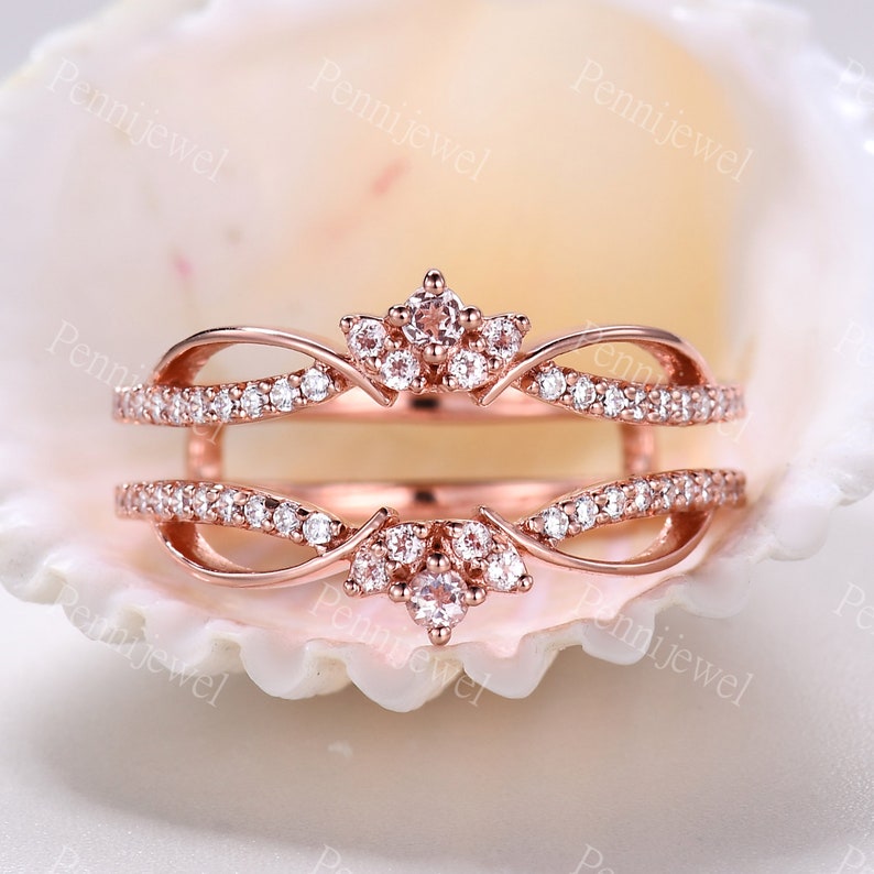 K&ouml;nnte beinhalten: Ros&eacute;goldener Ringverst&auml;rker mit einem zarten, kronenartigen Design, das mit einer Gruppe kleiner, klarer Steine besetzt ist. Der Verst&auml;rker ist mit einer Reihe kleinerer Steine entlang der Band besetzt.