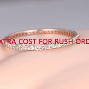 May include: A delicate rose gold band ring with a row of small diamonds encircling the band. "EXTRA COST FOR RUSH ORDER" is written in red text on the image.