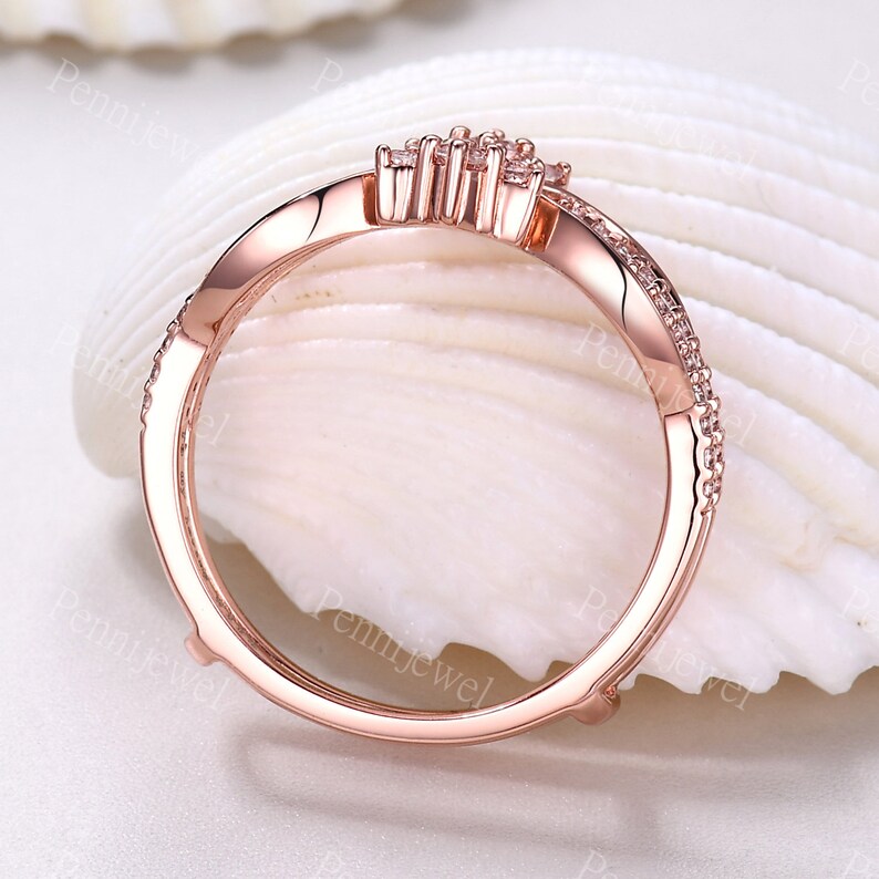 K&ouml;nnte beinhalten: Ein Ring aus Ros&eacute;gold mit einem zarten Design, das einen Cluster aus kleinen, klaren Steinen zeigt. Der Ring liegt auf einem wei&szlig;en Hintergrund.
