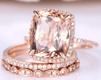 May include: A rose gold engagement ring set with a large, cushion-cut morganite center stone surrounded by a halo of smaller diamonds. The ring is paired with two matching bands, one with a row of diamonds and the other with a more intricate design.