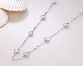 May include: A silver chain necklace with round clear stones. The necklace is on a white background.