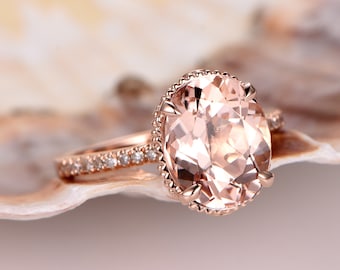 Op de afbeelding: Een verlovingsring van roségoud met een grote ovale morganiet-edelsteen, omringd door een halo van kleinere diamanten. De band is ook bezet met kleinere diamanten.