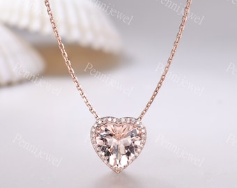 May include: A delicate rose gold necklace with a heart-shaped pendant featuring a large, light pink gemstone surrounded by a halo of smaller, sparkling gemstones.