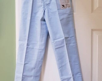 May include: Light blue pants hanging on a black hanger against a white door. The pants have a label on the right leg.