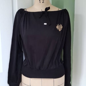 Vintage never worn deadstock 1970s black off-the-shoulder knitted top with gold motif detail