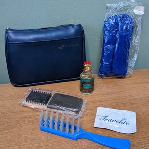 May include: A blue wash bag with the Air Florida logo, a small bottle of cologne, a blue eye mask, a travel-sized hairbrush, and a small white card with the text "Travelite" on it.