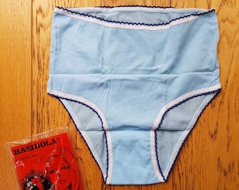 Puede incluir: Bóxer azul claro con ribete blanco y azul. La ropa interior tiene un borde festoneado y el nombre de la marca "BAMBOLA" está impreso en el embalaje.