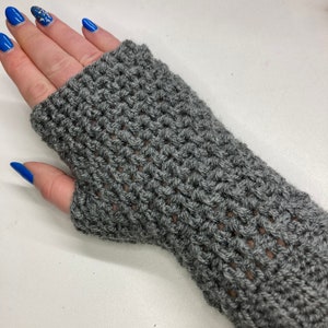 Puede incluir: Guantes sin dedos grises con un diseño de ganchillo.