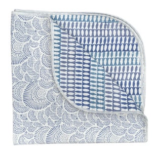 May include: A blue and white cotton quilt with a geometric pattern on one side and a floral pattern on the other side.