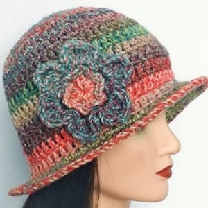 May include: A crocheted hat with a large flower design in shades of red, green, brown, and blue.