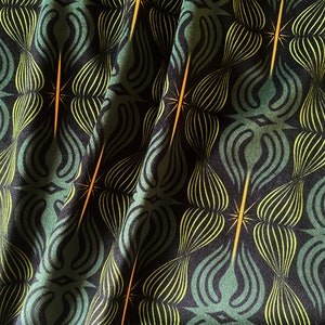May include: Green and yellow fabric with a repeating pattern of stylised floral shapes. The fabric has a subtle sheen and a textured surface.