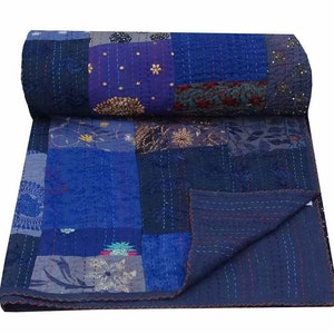 May include: A blue and purple kantha quilt with a patchwork design. The quilt is made from recycled saris and features intricate embroidery and stitching.