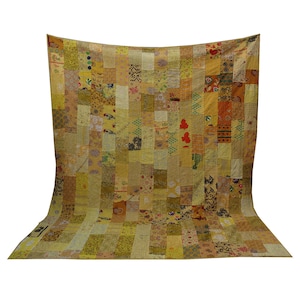 May include: A large, yellow and brown patchwork quilt with a variety of patterns and colours. The quilt is made of many different pieces of fabric sewn together.
