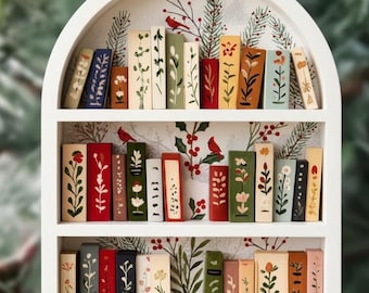 May include: A white wooden bookshelf ornament with three shelves filled with miniature, hand-painted books. The books feature floral and botanical designs in various colours. The background has a festive pattern with birds and greenery, and a gold string for hanging.