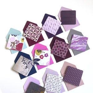 Puede incluir: Un conjunto de 10 pequeñas tarjetas cuadradas con varios patrones y diseños. Las tarjetas son en tonos de morado, rosa y gris. Las tarjetas están dispuestas en semicírculo sobre un fondo blanco. Las tarjetas están en blanco y se pueden usar para escribir notas, mensajes o saludos.