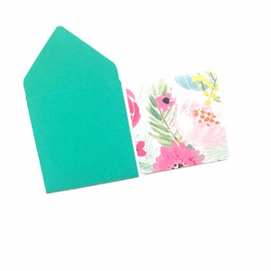 May include: A teal envelope with a floral design on the back. The envelope is blank on the front.