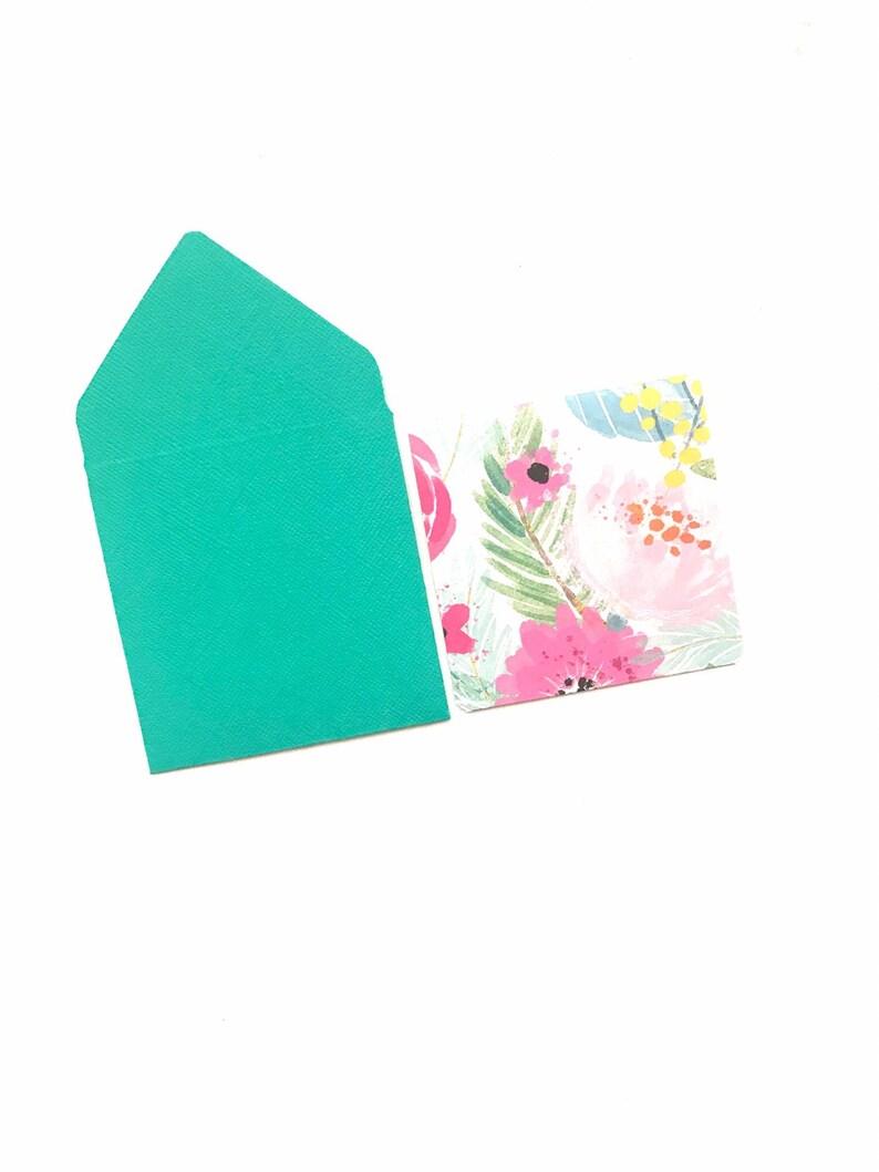 May include: A teal envelope with a floral design on the back. The envelope is blank on the front.
