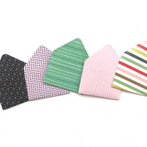 May include: Five small envelopes with different patterned designs. The envelopes are in black and white, purple and white, green and white, pink and white, and multi-colored stripes.