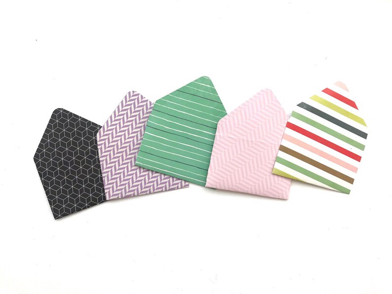 May include: Five small envelopes with different patterned designs. The envelopes are in black and white, purple and white, green and white, pink and white, and multi-colored stripes.