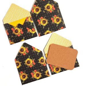 May include: Set of four small envelopes with a sunflower and polka dot pattern. The envelopes are black with yellow sunflowers and red polka dots. The inside of the envelopes is lined with yellow and white stripes.