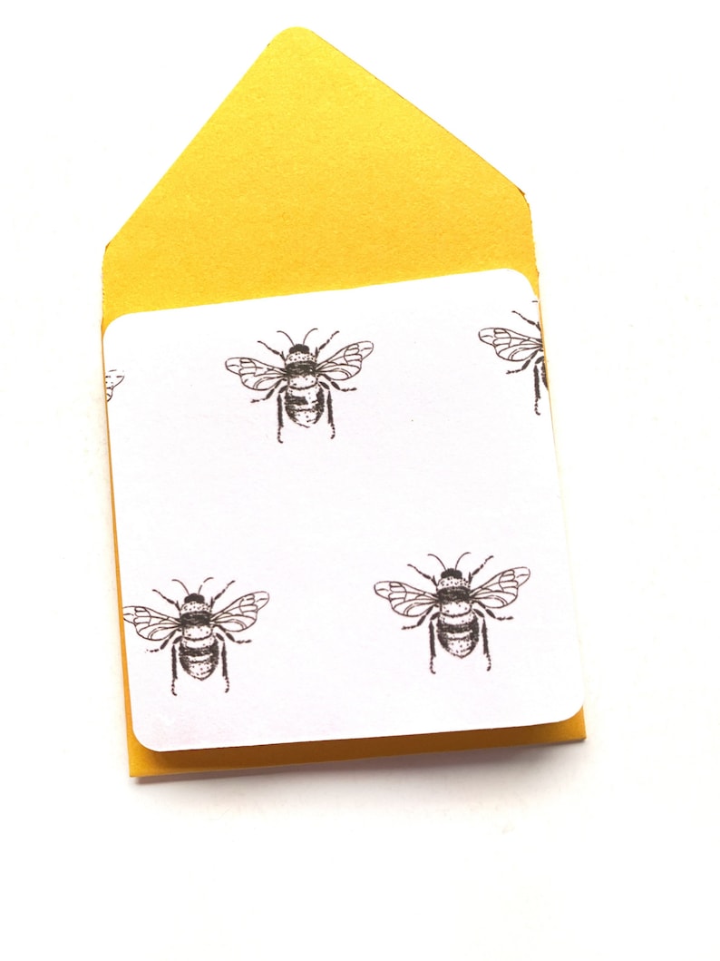 May include: A yellow envelope with a white card inside. The card has a repeating pattern of black and white bee illustrations.