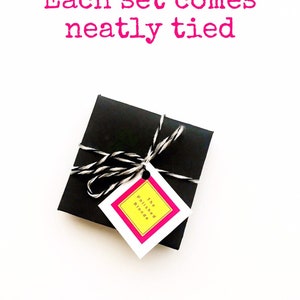 May include: A small black box tied with black and white twine. The box has a tag attached that says "The Polished Blonde".