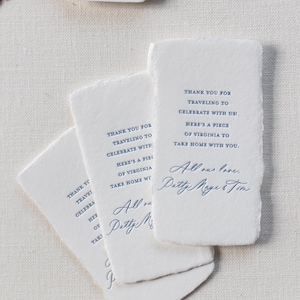 May include: White rectangular cards with deckled edges, featuring blue text. The cards read "Thank you for traveling to celebrate with us! Here's a piece of Virginia to take home with you." and are signed "Patty Meyer & Tim."