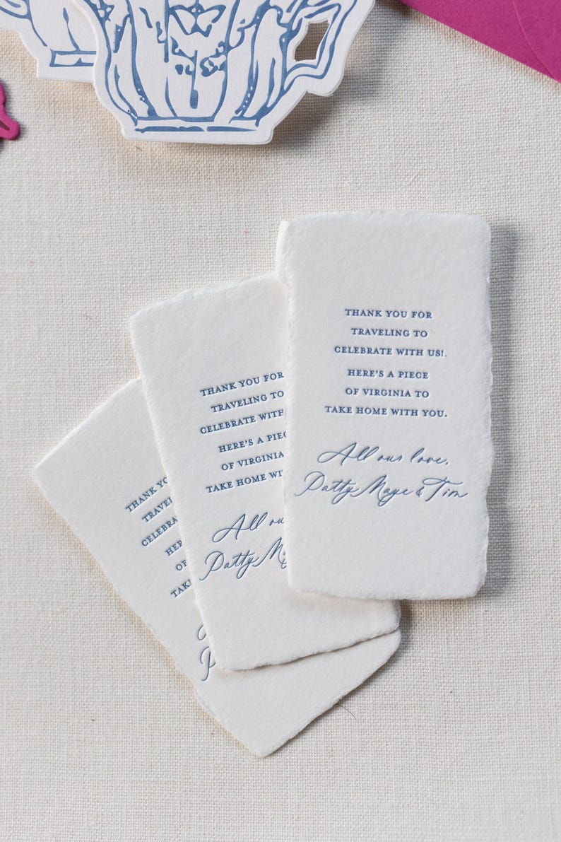May include: White rectangular cards with deckled edges, featuring blue text. The cards read "Thank you for traveling to celebrate with us! Here's a piece of Virginia to take home with you." and are signed "Patty Meyer & Tim."