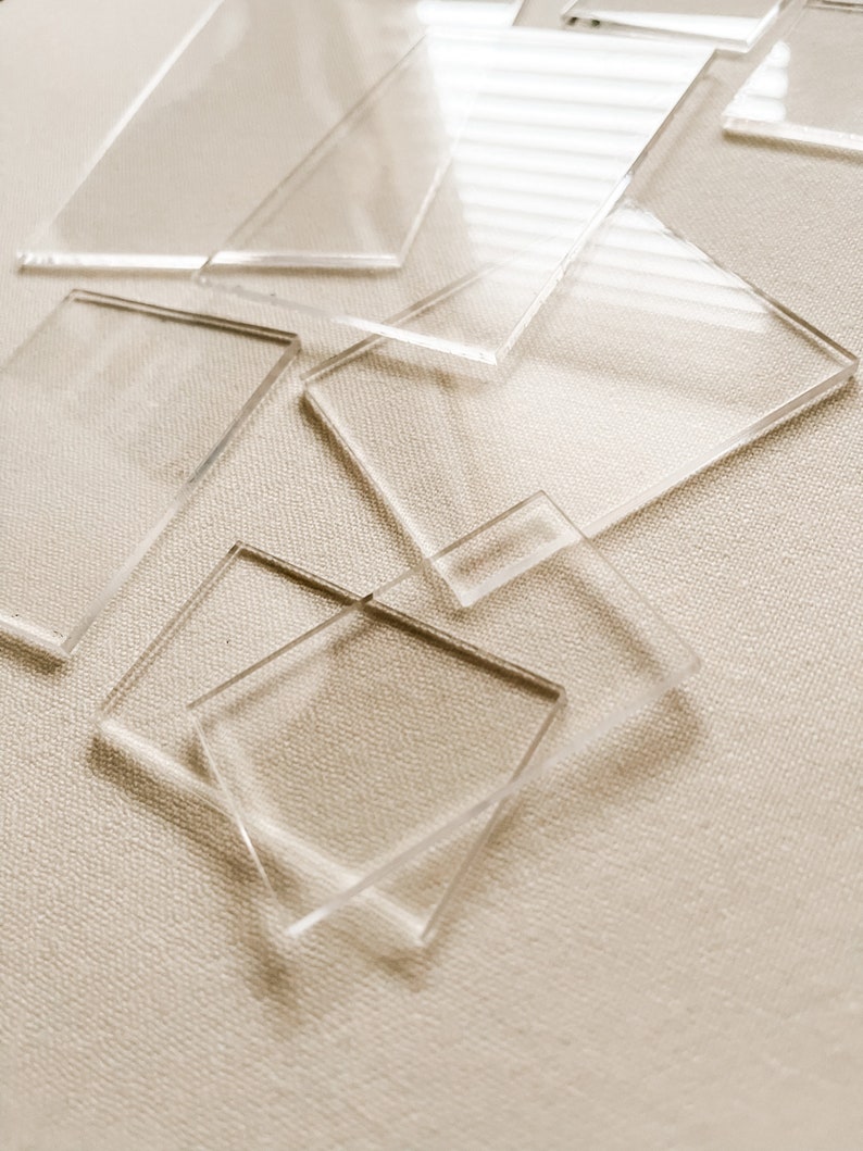 May include: A group of clear acrylic squares of various sizes stacked on top of each other. The squares are arranged in a random pattern and are slightly overlapping.