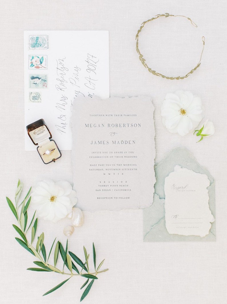 May include: Wedding invitation suite with a white background and blue and green accents. The invitation features the names Megan Robertson and James Madden, the date and time of the wedding, and the location. The RSVP card is also included.