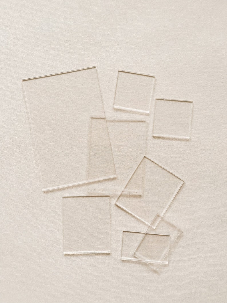 May include: A set of seven clear acrylic squares of varying sizes, arranged on a white background.