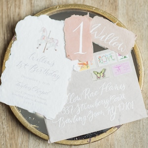 May include: A white card with the text "Willow's 1st Birthday" and the date "December 1, 2015". The card also includes the text "Taylors Chapel" and an address. The card is on a gold tray with a pink card with the number "1" and a white card with the text "Willow".