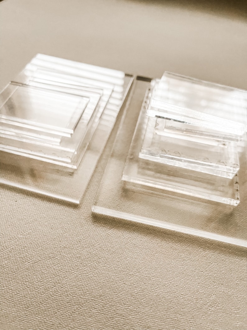 May include: Two stacks of clear acrylic squares of varying sizes. The squares are stacked on top of each other, creating a tiered effect.