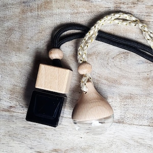 May include: Two car air fresheners with wooden and black square accents. One has a clear glass bottom. The other has a wooden block and black square. Both have black and gold braided cords for hanging.
