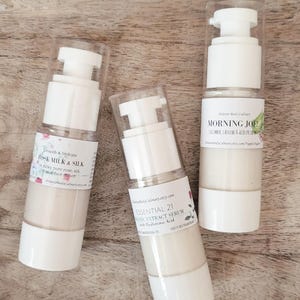 Może przedstawiać: Trzy białe butelki z pompkami zawierające produkty do pielęgnacji sk&oacute;ry. Butelki są oznaczone nazwami "Rose Milk & Silk", "Essential 21 Organic Extract Serum with Hyaluronic Acid" i "Morning Joe! Cucumber, Caffeine & Aloe Eye Cream".