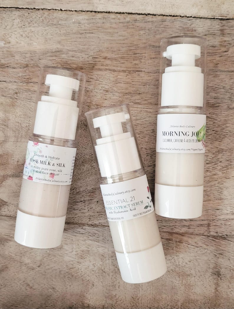 Może przedstawiać: Trzy białe butelki z pompkami zawierające produkty do pielęgnacji sk&oacute;ry. Butelki są oznaczone nazwami "Rose Milk & Silk", "Essential 21 Organic Extract Serum with Hyaluronic Acid" i "Morning Joe! Cucumber, Caffeine & Aloe Eye Cream".