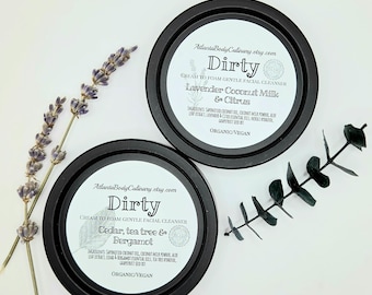May include: Two round black containers of Dirty cream to foam gentle facial cleanser. One label reads Lavender Coconut Milk & Citrus, the other Cedar, tea tree & Bergamot. Both include organic and vegan text, ingredients, and a sprig of lavender.